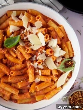 Overhead image of a bowl of spicy rigatoni pasta, generously topped with grated Parmesan cheese.