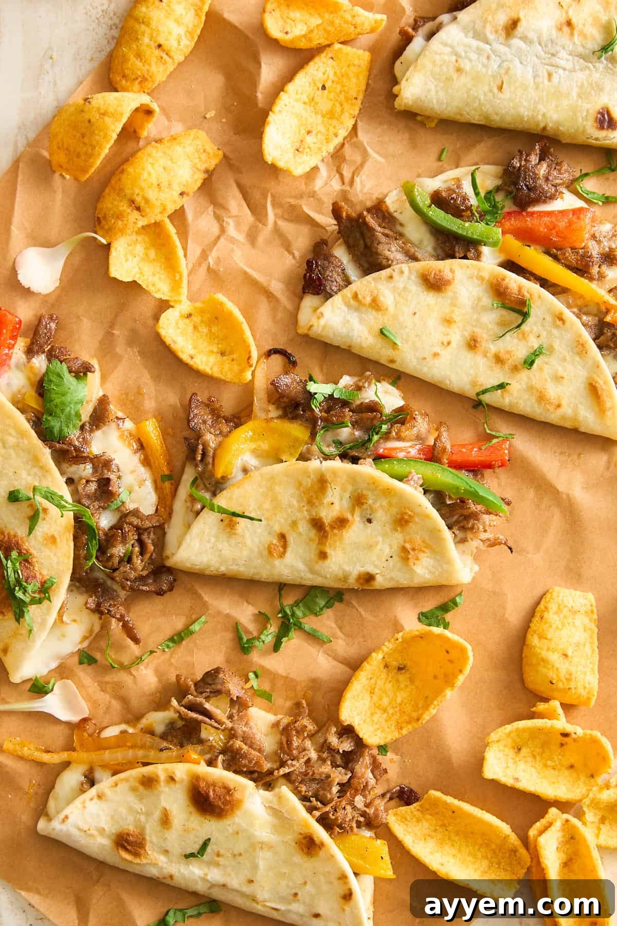 A group of Philly cheesesteak tacos artfully arranged on parchment paper, ready to be enjoyed.