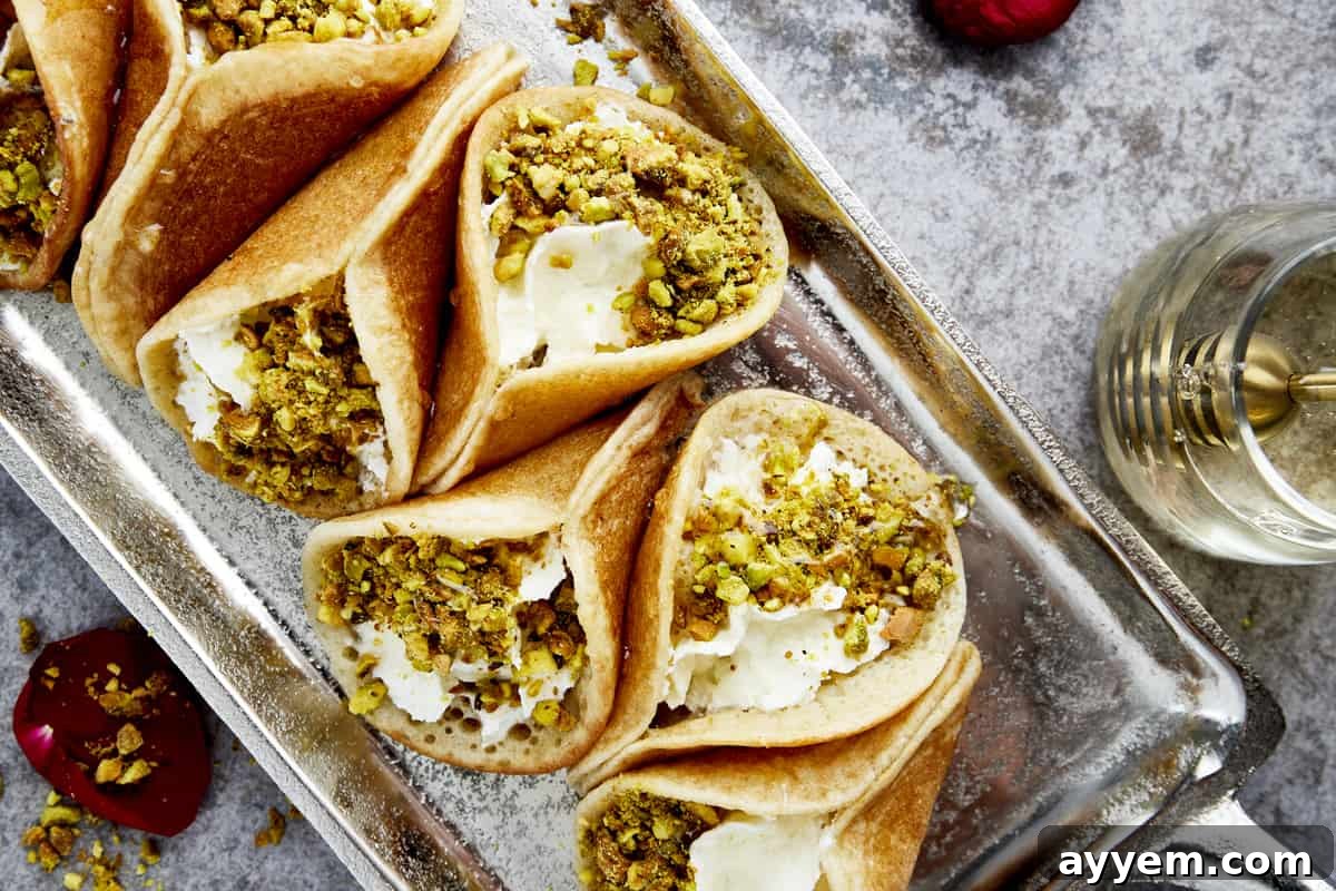 A beautiful platter of atayef filled with rich cream cheese and topped with crushed pistachios, a traditional and beloved Ramadan dessert.