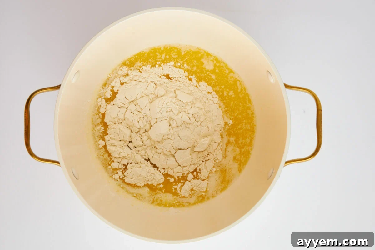 All-purpose flour being whisked into melted butter in a saucepan.
