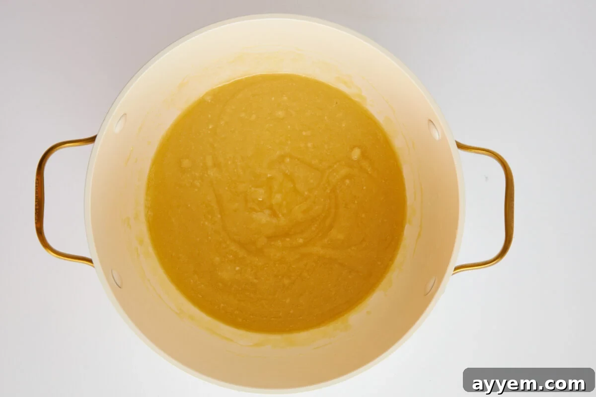 A thick, pale roux being cooked in a pot.